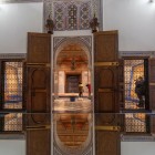 Portale elegante in legno scolpito con stucchi e mosaici zellige incornicia l’ingresso del palazzo, preludio all’arte tradizionale marocchina. 