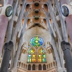 La navata della Sagrada Família conduce lo sguardo verso l’abside, dove colonne ramificate, volte geometriche e vetrate policrome compongono la basilica-foresta di Gaudí.