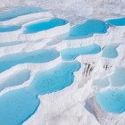 Pamukkale, il “castello di cotone” turco, incanta con le sue terrazze di travertino bianco e acque termali curative.
