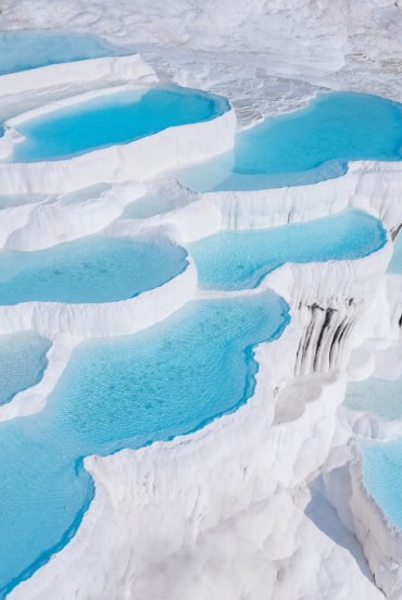 Terrazze di travertino bianche a Pamukkale con piscine naturali ricche di minerali curativi, un paesaggio unico e storico.