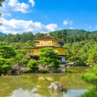Splendida vista del Golden Pavilion (Kinkaku-ji) a Kyoto, tempio dorato immerso nella natura, riflesso in uno stagno che esalta la sua bellezza e l’armonia del paesaggio giapponese.