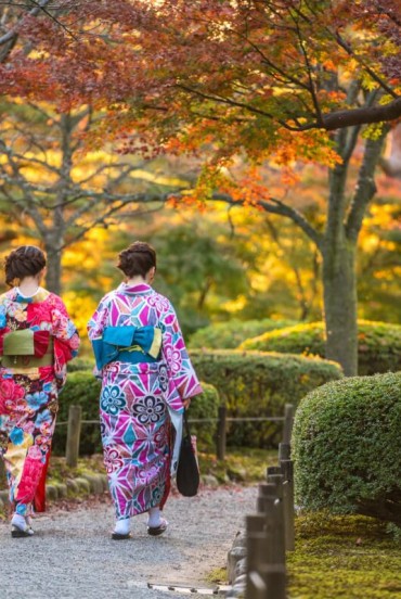 Ragazze con vestiti tradizionali a passeggio nei viali del parco Kenroku-en a Kanazawa nella prefettura di Ishikawa considerato uno dei tre giardini più belli del Giappone.