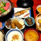 Una cena tipica in un ryokan a Takayama include piatti kaiseki con sashimi, sukiyaki, tempura, pickles, riso e pesce grigliato, accompagnati da sake locale, in un ambiente sereno e raffinato.