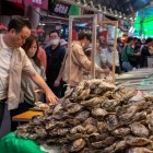 Nel Mercato di Omicho a Kanazawa, uno stand offre ostriche fresche provenienti dal Mar del Giappone, servite con condimenti come limone o salsa ponzu, per un'esperienza autentica.