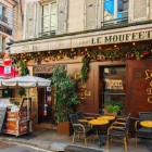 Un tipico ristorante parigino su Rue Mouffetard, nel Quartiere Latino, accoglie con tavolini all’aperto, profumi invitanti e l’atmosfera vivace delle stradine storiche di Parigi.