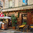 Un tipico ristorante parigino su Rue Mouffetard, nel Quartiere Latino, accoglie con tavolini all’aperto, profumi invitanti e l’atmosfera vivace delle stradine storiche di Parigi.