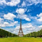 Il verde del Campo di Marte si apre come un grande tappeto erboso, attraversato da viali alberati e fioriture colorate, mentre la Torre Eiffel domina lo sfondo con eleganza.
