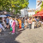 Turisti la pittoresca Place du Tertre: tra cavalletti colorati, si fermano per un ritratto o una caricatura, sorseggiano caffè sulle terrazze animate, immersi nella vibrante atmosfera