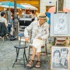 Un caricaturista di strada a Montmartre ritrae turisti con tratti rapidi e ironici. Tra cavalletti e colori, il suo talento cattura l’anima del quartiere più bohémien di Parigi.
