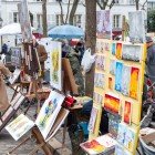 Turisti e artisti invadono le vie di Place du Tertre: cavalletti colorati, caricaturisti all’opera e terrazze accoglienti dove sorseggiare un caffè immersi nell'atmosfera bohemien