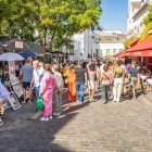 Turisti la pittoresca Place du Tertre: tra cavalletti colorati, si fermano per un ritratto o una caricatura, sorseggiano caffè sulle terrazze animate, immersi nella vibrante atmosfera