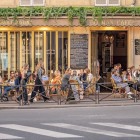 Nel vivace quartiere Pigalle di Parigi, un caffè tradizionale accoglie clienti tra tavolini all’aperto e l’atmosfera tipica dei bistrot parigini più autentici.