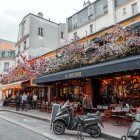 Tipico caffè parigino decorato con fiori e tavoli all’aperto su Rue des Abbesses, Parigi, Francia.