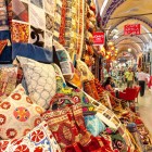 Tessuti, cuscini, tappeti, kilim e foulard dai colori vivaci al Gran Bazaar di Istanbul, dove arte e cultura si intrecciano in creazioni uniche.