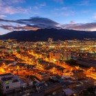 Lo skyline di Quito al tramonto si illumina sotto il vulcano Pichincha, creando un paesaggio unico dove natura e città si fondono in uno scenario iconico dell’Ecuador.