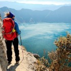 Una giovane turista ammira lo spettacolare panorama del Quilotoa, il lago vulcanico verde tra le Ande dell’Ecuador, meraviglia naturale del Sud America.
