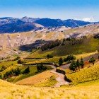 Paesaggio andino pittoresco in Ecuador, tra il Canyon di Zumbahua e la Laguna Quilotoa, con una strada sterrata che attraversa campi coltivati e scenari montani.