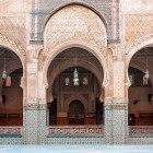 Gli archi della Medersa di Fès mostrano intagli geometrici e arabeschi raffinati, simbolo dell’arte islamica e maestria artigianale del XIV secolo.