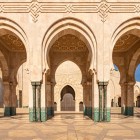 Gli archi esterni della Moschea di Hassan II sfoggiano mosaici intricati e motivi islamici, espressione d’arte marocchina e maestria artigianale senza pari.