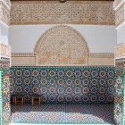 Il porticato attorno al cortile della Medersa Ben Youssef è decorato con mosaici zellige geometrici, intagli in legno e stucco, simbolo dell’arte andalusa e maestria locale.