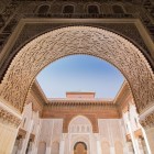 Dettagli dell'ingresso principale della Medersa Ben Youssef: maestoso arco a ferro di cavallo finemente decorato con intagli in legno di cedro.