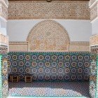 Il porticato attorno al cortile della Medersa Ben Youssef è decorato con mosaici zellige geometrici, intagli in legno e stucco, simbolo dell’arte andalusa e maestria locale.
