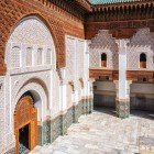 Le pareti del cortile della Medersa Ben Youssef mostrano zellige multicolori in basso e intagli in stucco sopra, con finestre in legno intagliato artigianale.