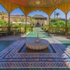 La fontana centrale del Secret Garden a Marrakech, collegata al tradizionale impianto idrico, riflette piante e vialetti creando un’oasi di serenità.