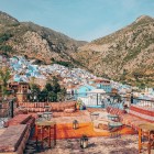 Chefchaouen si apre tra le montagne con le sue case blu brillanti che si fondono nel paesaggio, offrendo una vista mozzafiato di natura e tradizione marocchina.
