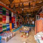 Nel souq interno, tessuti colorati e abiti tradizionali marocchini si intrecciano tra botteghe, rivelando l’eleganza dell’artigianato locale.