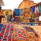 Nel souk all’aperto di Aït Ben Haddou le bancarelle offrono artigianato locale, tessuti, tappeti e ceramiche tra vicoli e cortili tradizionali.