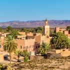 Vista panoramica di Ouarzazate tra kasbah in terra cruda, palmeti e montagne dell’Atlante, porta d’accesso al deserto e set cinematografico famoso.