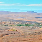 Dall’alto, la Valle Ounila mostra un paesaggio di colline e valli, con villaggi berberi e kasbah in terra rossa che si fondono armoniosamente con la natura circostante.