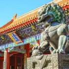Le statue di leoni guardiani e i tetti gialli con decorazioni dorate simboleggiano protezione e potere imperiale nella Città Proibita di Pechino.