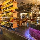 Elegante wine bar del Ramada Istanbul Pera, tra luci calde e scaffalature in legno per una degustazione unica e raffinata.