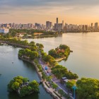 Panorama di Hanoi al tramonto: il Lago dell’Ovest riflette il cielo dorato, con il tempio Tran Quoc e lo skyline moderno che creano un contrasto armonioso.