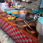Bancarella di cibo tradizionale con mole, nopales e peperoncini in pentole di terracotta al mercato El Parián di Puebla, Messico