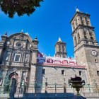 La facciata della Cattedrale di Puebla colpisce con il suo stile barocco severo, le alte torri gemelle e i dettagli scolpiti che emergono sullo sfondo del cielo limpido e intenso.