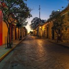 Strada di Oaxaca all’alba, illuminata da una luce dorata che accarezza le facciate coloniali color pastello. Un’atmosfera calma e autentica nel cuore dello storico stato di Oaxaca, in Messico.