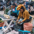 Donne indigene messicane al mercato di San Cristóbal de Las Casas espongono verdure fresche su colorati teli artigianali, mantenendo vive tradizioni antiche in un’atmosfera autentica e vibrante.
