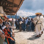 Indigeni messicani riuniti in piazza indossano abiti tradizionali tzotzil, con cappelli colorati, nastri vivaci e mantelli di lana, in una scena autentica di cultura locale.
