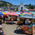 Nel mercato di San Cristóbal de Las Casas, ombrelloni colorati riparano gli indigeni che vendono prodotti artigianali e alimenti locali, creando un vivace mosaico di culture, tradizioni e colori.