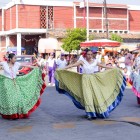 Giovani danzatrici a Tehuantepec eseguono coreografie tradizionali indossando ampie gonne colorate e fiori tra i capelli, mentre la folla osserva la scena in un’atmosfera festosa e vivace.