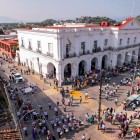 Veduta aerea della piazza di Tehuantepec animata da una folla festosa, con il grande Palazzo Municipale bianco che domina la scena tra bancarelle, musica e colori tipici del Messico.