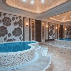 Elegante area wellness con piscine idromassaggio, mosaici decorativi e luci soffuse. Un ambiente raffinato e rilassante, ideale per momenti di benessere e comfort esclusivo.