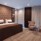 Camera matrimoniale elegante e moderna con letto king size, testiera imbottita, arredi raffinati e area relax con poltrone. Ambiente luminoso, confortevole e curato nei dettagli.