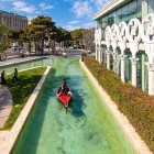 Suggestivo scorcio urbano a Baku con canale artificiale, barca turistica e architettura elegante. Un angolo moderno tra verde, acqua e atmosfera rilassante.