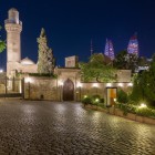 Il Palazzo degli Shirvanshah di notte a Baku affascina con cupole e minareti illuminati, tra mura antiche e skyline moderno sullo sfondo.