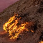 La Montagna di Fuoco di Yanardag in Azerbaigian mostra fiamme naturali che bruciano lungo il pendio roccioso, alimentate da gas sotterraneo in uno scenario suggestivo al tramonto.