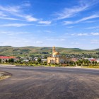 La foto mostra la moschea di Mereze, in Azerbaigian, con cupola dorata al centro del villaggio, circondata da case e colline verdi, in un paesaggio rurale autentico e tranquillo.